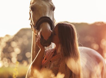 Love picture with Bohemian lady in boho style fashion kissing a white horse 